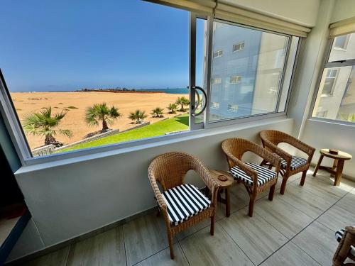a room with chairs and a window with a view of a beach at Ocean Dream Sunset Sails in Swakopmund