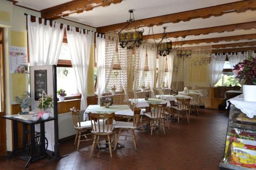 una sala da pranzo con tavoli, sedie e finestre di Appartamenti Vacanze Lagolo a Lagolo di Calavino