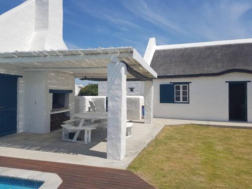 een wit huis met een patio met een picknicktafel bij Ocean Breeze Cottage, Cape Agulhas in Struisbaai