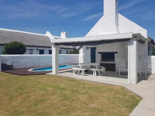 een witte kerk met een picknicktafel en een zwembad bij Ocean Breeze Cottage, Cape Agulhas in Struisbaai