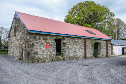 an old stone barn with a red roof at Marianne Cottage at Johnsfort in Ráistín