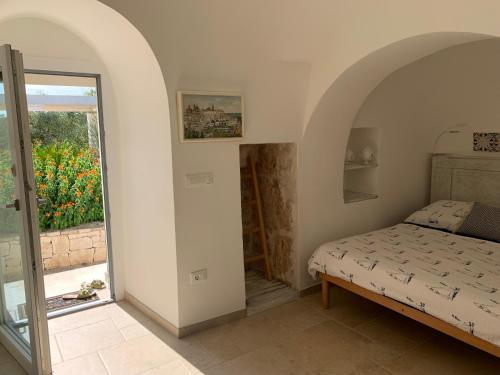 a bedroom with a bed and a door to a balcony at IL Quieto Uliveto in Ostuni