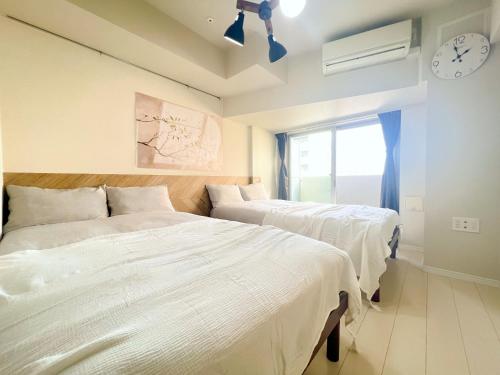 a bedroom with two beds and a clock on the wall at Shinjuku Downtown BZT Free WiFi in Tokyo