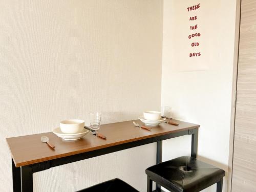 a wooden table with two cups and a stool at Shinjuku Downtown BZT Free WiFi in Tokyo