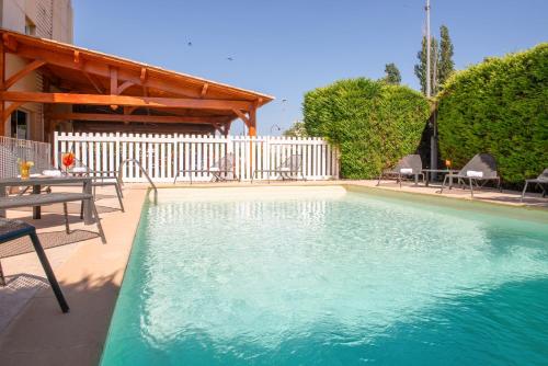 - une piscine avec des chaises, une table et une clôture dans l'établissement The Originals City, Hôtel La Belle Étape, Brignoles, à Brignoles