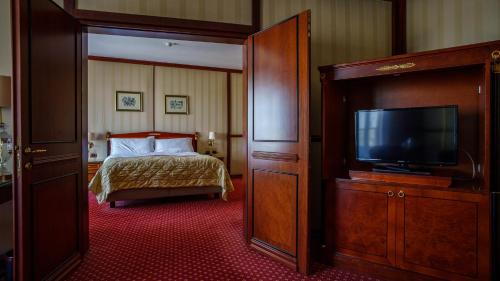 a hotel room with a bed and a flat screen tv at Grand Hotel Bucharest in Bucharest