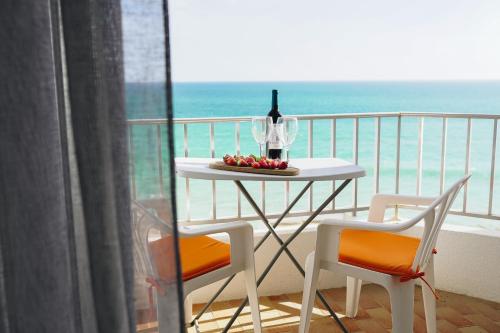 a table with a bottle of wine and two chairs on a balcony at Host Wise - Terrace & Ocean View Flat in Armação de Pêra
