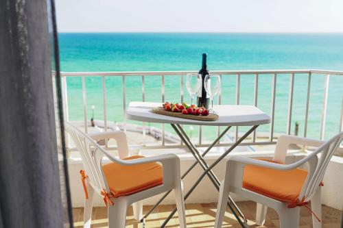 a table with a bottle of wine and fruit on a balcony at Host Wise - Terrace & Ocean View Flat in Armação de Pêra