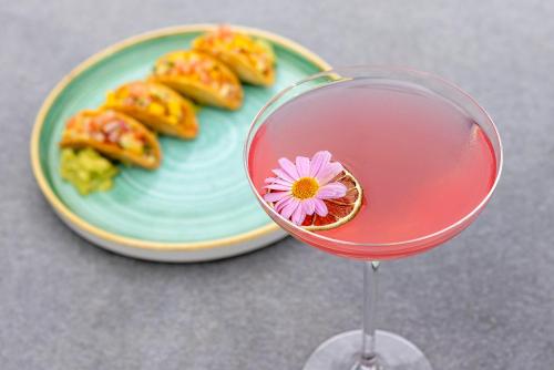 a pink drink in a glass next to a plate of food at Gonville Hotel in Cambridge