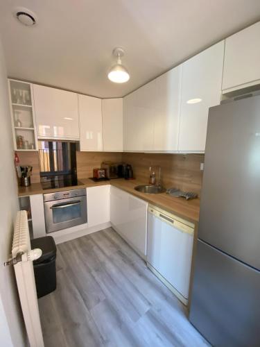 une cuisine avec des armoires blanches et un réfrigérateur en acier inoxydable dans l'établissement Standing au cœur de Bonneville, à Bonneville