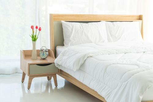 a bed with white sheets and a table with a vase of flowers at Elet Business Hotel in Karachi