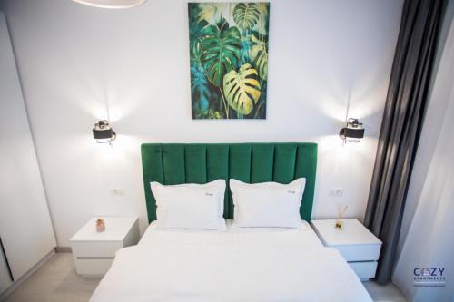 ein Schlafzimmer mit einem weißen Bett mit grünem Kopfteil in der Unterkunft Exclusive Cozy Apartment Adora Park Arad in Arad