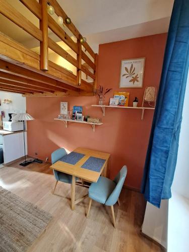 une salle à manger avec une table en bois et des chaises bleues dans l'établissement Charmant studio gare intra-muros, à Saint-Malo