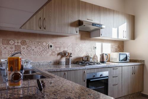 a kitchen with wooden cabinets and a counter top at Holmes Residence Tafraoute 2 in Tafraoute