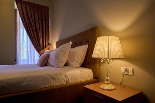 a bedroom with a bed with a lamp and a window at G Danube Boutique Hotel in Brăila
