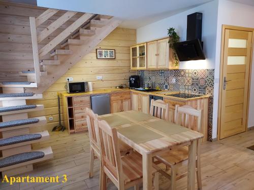 a kitchen with a wooden table and a staircase at Noclegi nad Czarną Orawą in Podwilk
