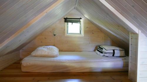 a bed in the attic of a wooden house at Nysted Strand Camping & Cottages in Nysted