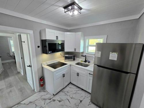 a kitchen with white cabinets and a stainless steel refrigerator at Casa moderna, a newly renovated Modern apartment in West Palm Beach