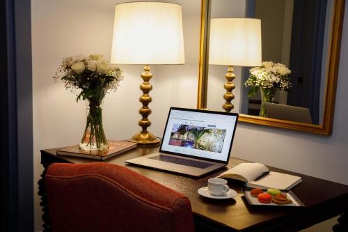 a laptop computer on a desk with a vase of flowers at Hagia Sofia Mansions Istanbul, Curio Collection by Hilton in Istanbul