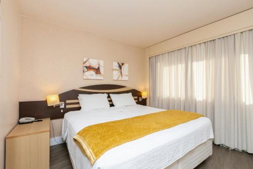 a hotel room with a large bed and a window at Tri Hotel Vittoria Bento in Bento Gonçalves