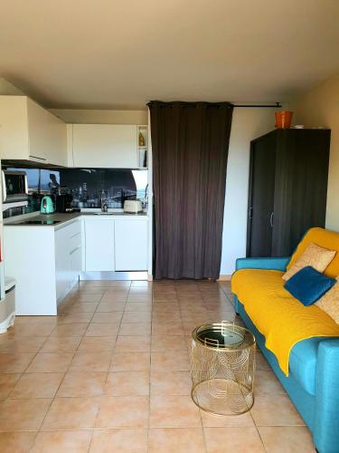 a living room with a blue couch and a kitchen at L'escapade Côte Bleue vue mer panoramique in Sausset-les-Pins