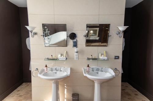 a bathroom with two sinks and mirrors on a wall at Château de La Mar Chambres d'Hôtes in Jongieux