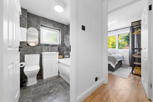 a bathroom with a toilet and a sink and a bed at Stylish 2BR Flat near Airport & Stadium, Sleeps 6 in Luton