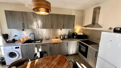 une cuisine avec une table et un réfrigérateur blanc dans l'établissement Au Cœur du Mont Dore 6 personnes, à Mont-Dore