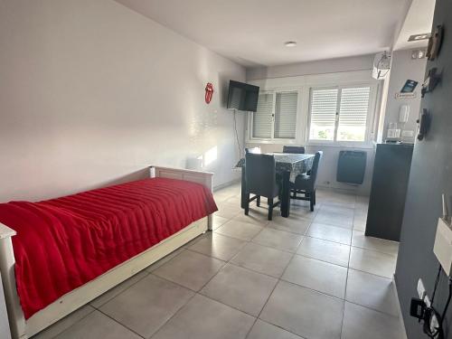 a bedroom with a bed with a red blanket and a table at Departamento por día para 4 personas con cochera cubierta en Bahía Blanca in Bahía Blanca
