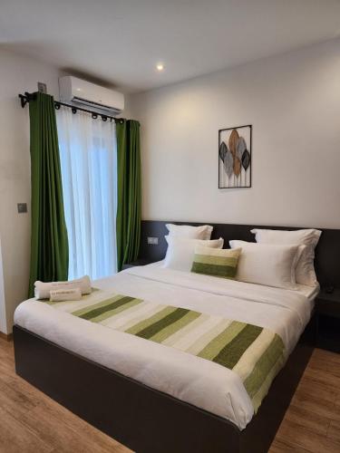 a bedroom with a large bed with green curtains at Miami Suites Tamatave in Toamasina