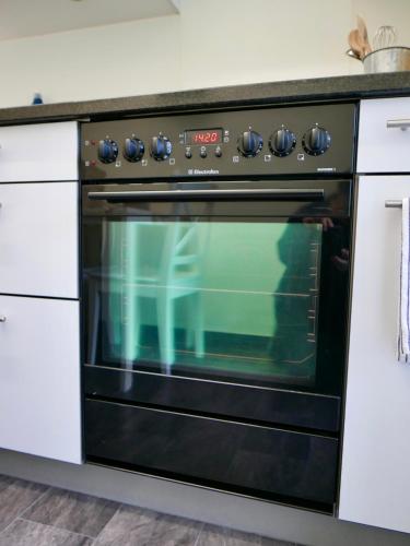 a black oven in a kitchen with white cabinets at Gemütliche Wohnung Nähe Uni in Basel