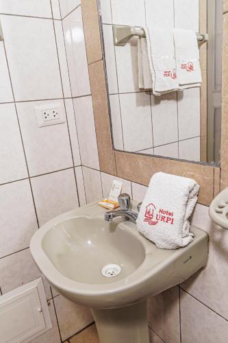 a bathroom with a sink and a mirror and towels at Hotel Urpi Cusco in Cusco