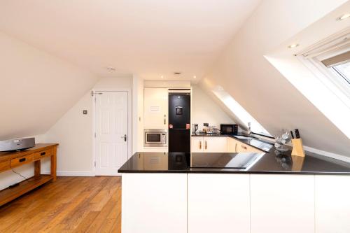 a kitchen with white cabinets and a black refrigerator at JOIVY Lovely Flats near the City Centre in Edinburgh