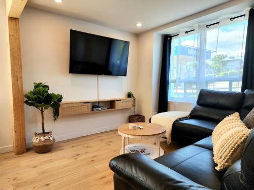 a living room with a couch and a tv on a wall at The Coziest - Hot Tub - EV Chrger & Free Parking in Quebec City