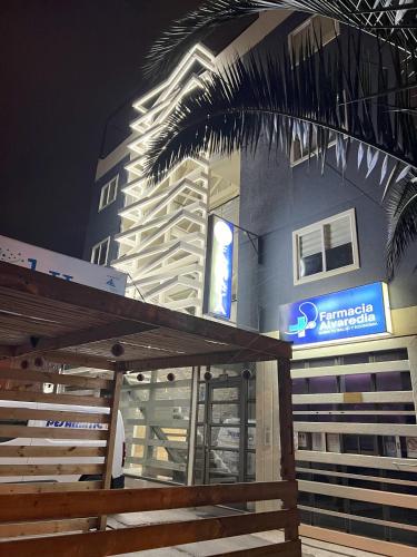 a building with a hotel sign and a palm tree at AH Hotel in Antofagasta