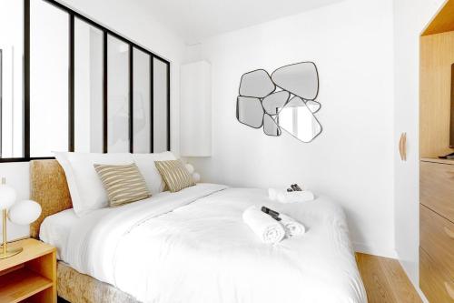 une chambre avec un lit blanc avec deux serviettes dessus dans l'établissement Suite Javel - Appartement à Paris, à Paris