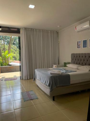 a bedroom with a bed and a large window at Da Orla Pampulha Hostel in Belo Horizonte