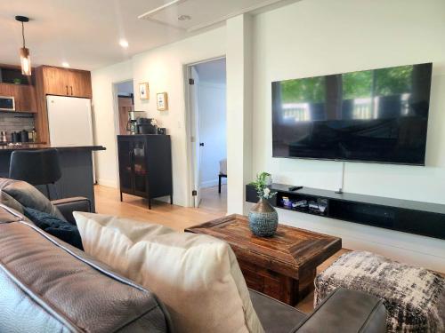 a living room with a couch and a table and a tv at Peaceful City View - Hot Tub - 2 Parking & EV Chrger in Quebec City