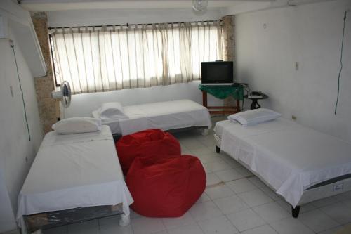 a room with three beds and a tv in it at Vivienda Turística El Castillo in Buritaca