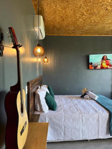 a bedroom with a guitar and a bed with a tv at OKA VIVAH - Chalé Oka do Sol in Jaboticatubas