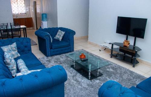 a living room with two blue couches and a television at Studio Apartment near the Airport in Nairobi