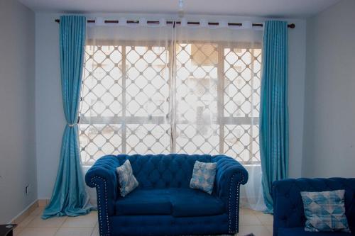 a blue couch in front of a window with blue curtains at Studio Apartment near the Airport in Nairobi