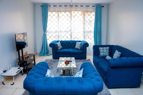 a living room with blue couches and a table at Studio Apartment near the Airport in Nairobi