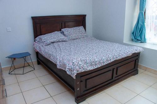 a bed with a wooden frame in a bedroom at Studio Apartment near the Airport in Nairobi