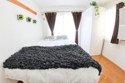 a bedroom with a large bed with a black blanket at ハイクレスト中野203 in Tokyo
