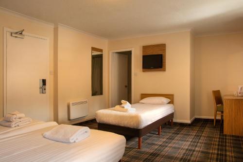 a hotel room with two beds and a tv at Britannia Edinburgh Hotel in Edinburgh
