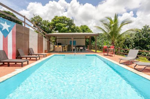 una grande piscina con sedie e gazebo di Finca Tapia Mountain Ranch a Fajardo