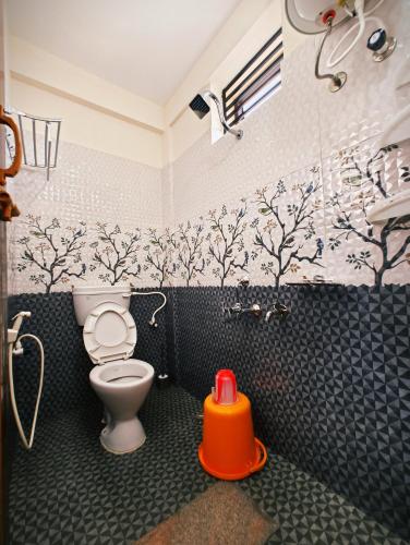 a bathroom with a toilet and trees on the wall at Nellakki Homestay in Madikeri
