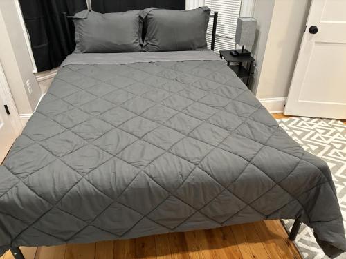 a bed with a gray comforter in a bedroom at HomeStay - B&B - Near South Boston - JFK-Umass Area in Boston