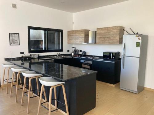 a kitchen with a black counter and a white refrigerator at Casa en Barrio Costa Esmeralda Pinamar in Costa Esmeralda